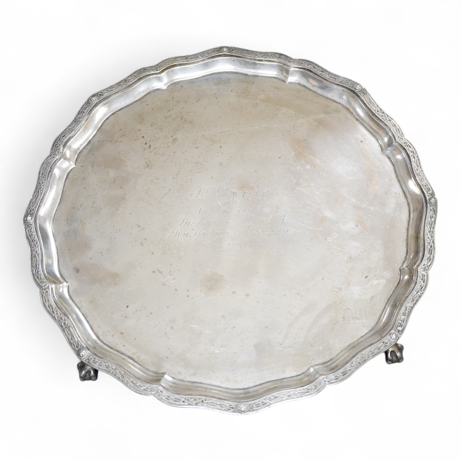 A George VI silver salver, of shaped circular form, on four claw and ball feet, with presentation inscription, Reid & Sons, London, 1936, 35.7cm, 40.5oz.